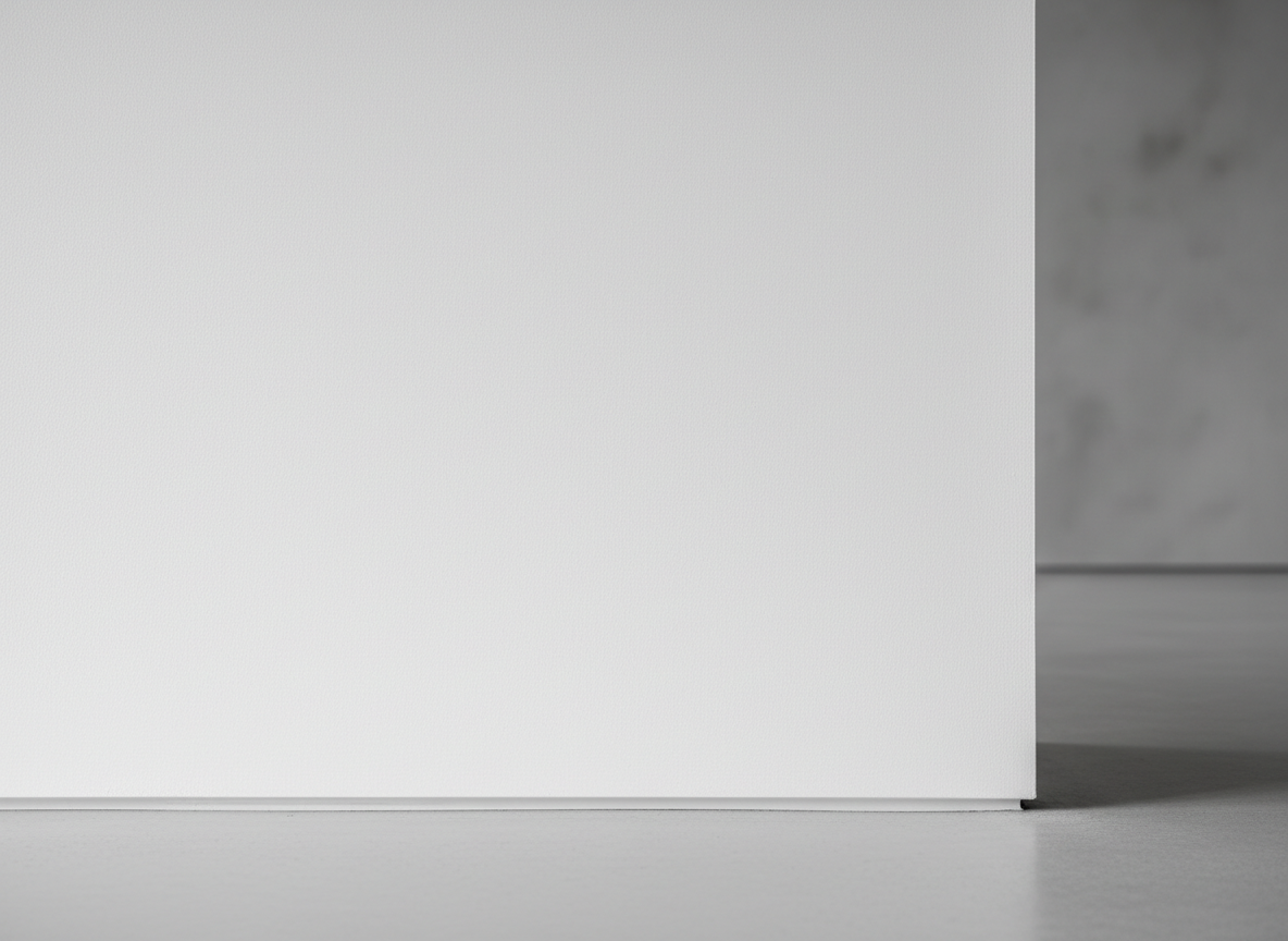 A close-up, photographic realism image of a sleek, matte-white interior wall coated with an advanced graphene-enhanced paint. The surface appears flawlessly smooth yet subtly textured, with a faint, almost metallic micro-sheen hinting at embedded graphene flakes. The wall meets a minimalist light-gray floor with a crisp, clean junction line, emphasizing precision application. Soft, diffused daylight from an unseen window grazes the surface from the left, revealing gentle gradients of light and shadow. The composition is simple and centered, shot at eye level with a shallow depth of field so the wall surface is in razor-sharp focus while the background fades into a soft blur. The mood is clinical, high-tech, and professional, conveying cutting-edge material science for interior coatings.